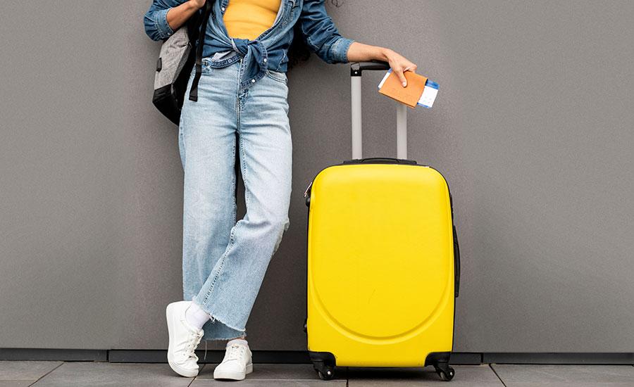 A woman posing with yellow luggage