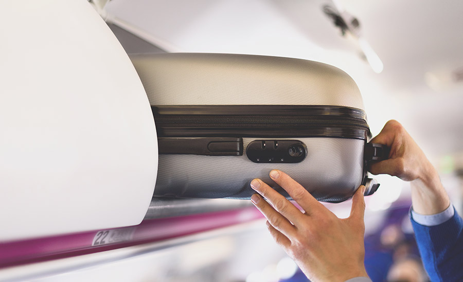 Carry-on luggage being stored in a plane's overhead bin